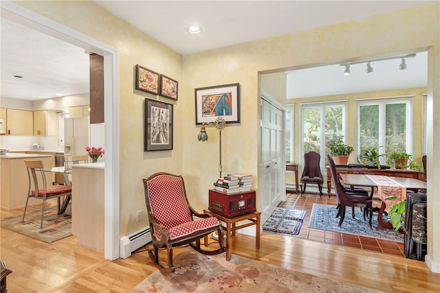 sitting room featuring rail lighting, light hardwood / wood-style floors, and a baseboard heating unit