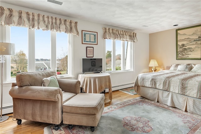 bedroom featuring light hardwood / wood-style floors and a baseboard heating unit