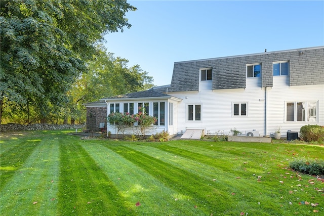 back of property featuring cooling unit and a lawn