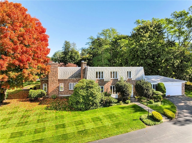 cape cod home with a garage and a front lawn