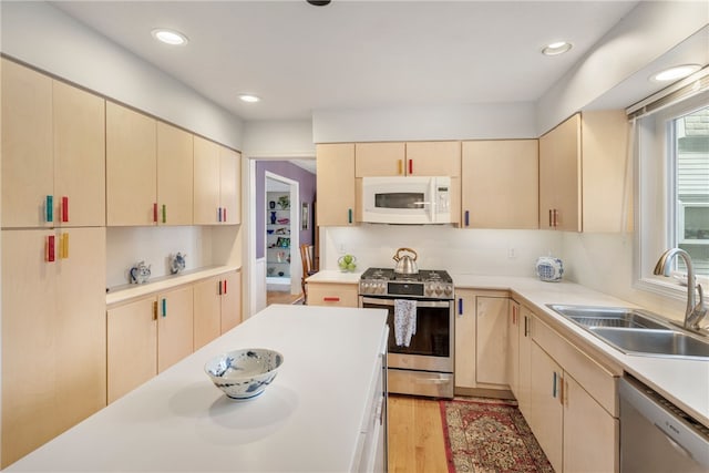 kitchen featuring appliances with stainless steel finishes, sink, light brown cabinets, and light hardwood / wood-style floors