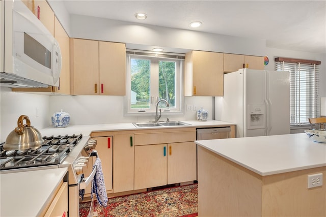 kitchen with stainless steel appliances, light brown cabinetry, sink, and a kitchen island