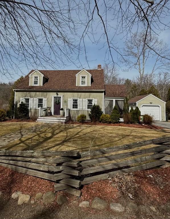 cape cod home featuring an outbuilding, a front yard, covered porch, a chimney, and a detached garage