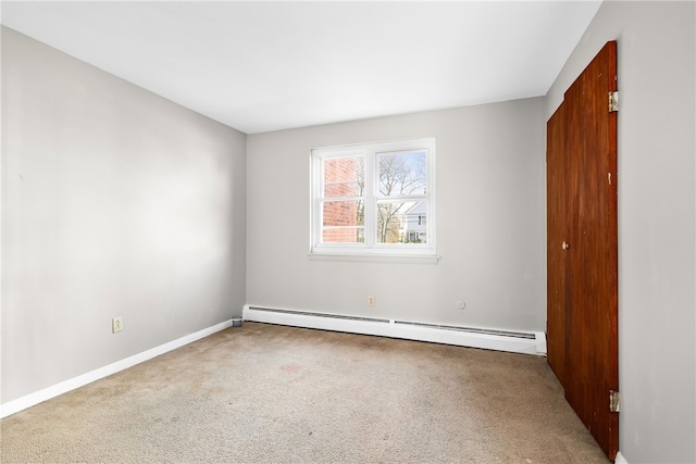 empty room with carpet floors and a baseboard heating unit