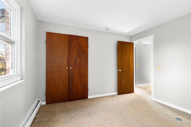 unfurnished bedroom featuring a baseboard radiator, light carpet, and a closet