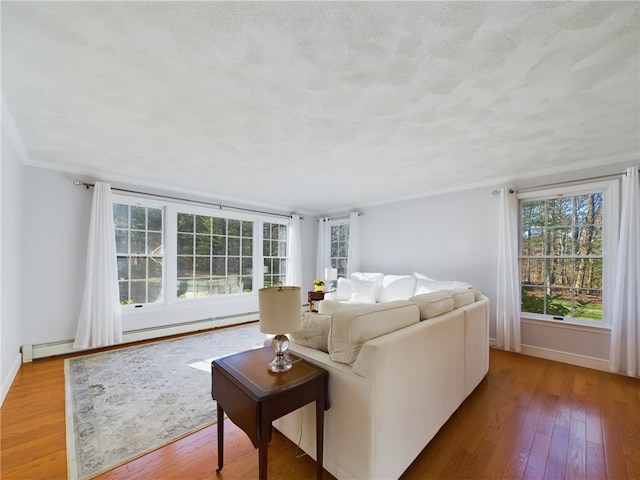 living room featuring a baseboard radiator, ornamental molding, light hardwood / wood-style flooring, and a textured ceiling