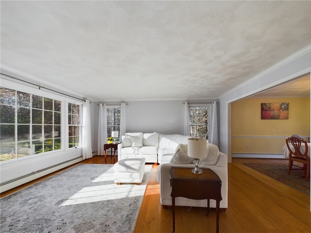 living room with baseboard heating, ornamental molding, wood-type flooring, and a textured ceiling