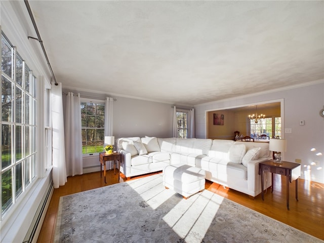 living room featuring baseboard heating, a notable chandelier, crown molding, and hardwood / wood-style flooring