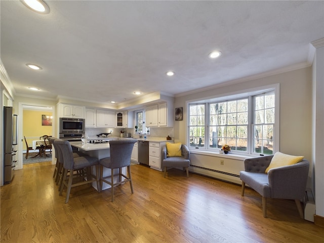 dining room with a baseboard radiator, crown molding, and light wood-type flooring