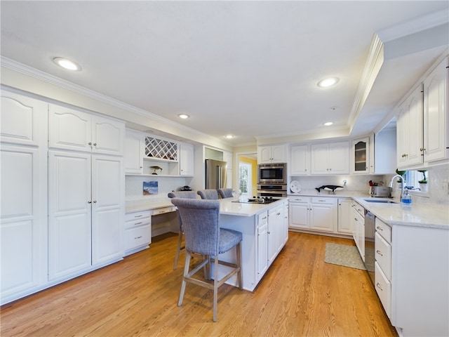 kitchen featuring appliances with stainless steel finishes, a breakfast bar, white cabinetry, sink, and a center island