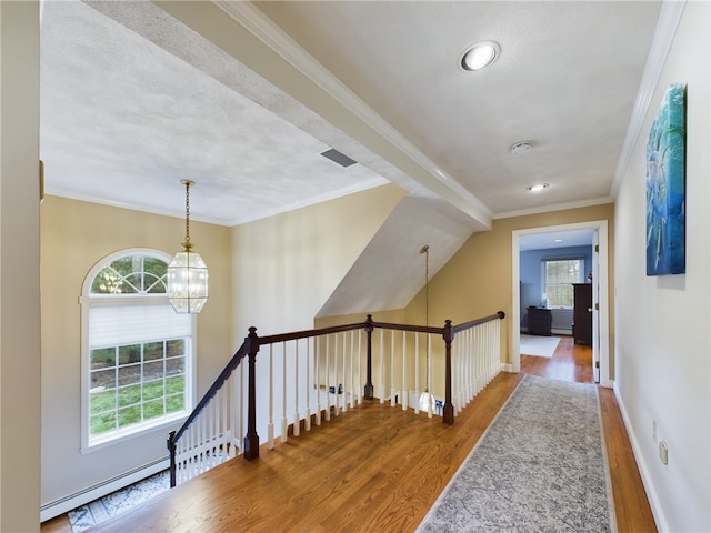 hall with hardwood / wood-style floors, lofted ceiling, ornamental molding, baseboard heating, and an inviting chandelier