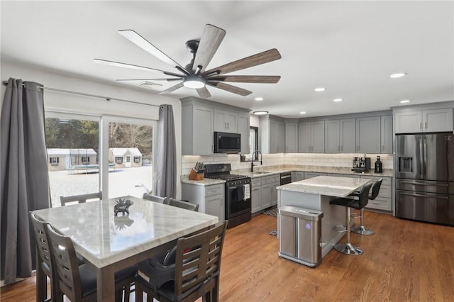 kitchen featuring sink, gray cabinetry, gas range, a center island, and stainless steel fridge with ice dispenser