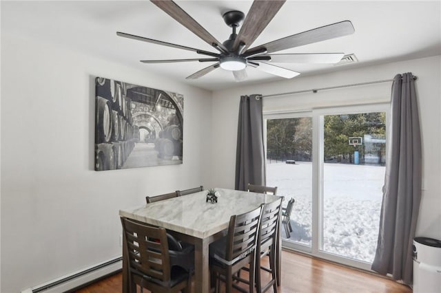 dining space featuring baseboard heating, ceiling fan, and hardwood / wood-style flooring