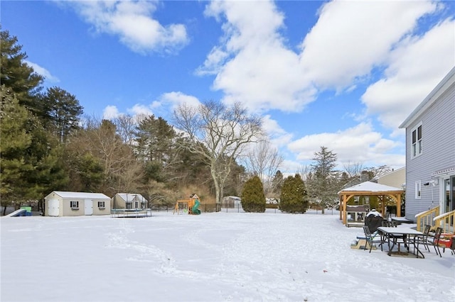 snowy yard featuring a gazebo and an outbuilding