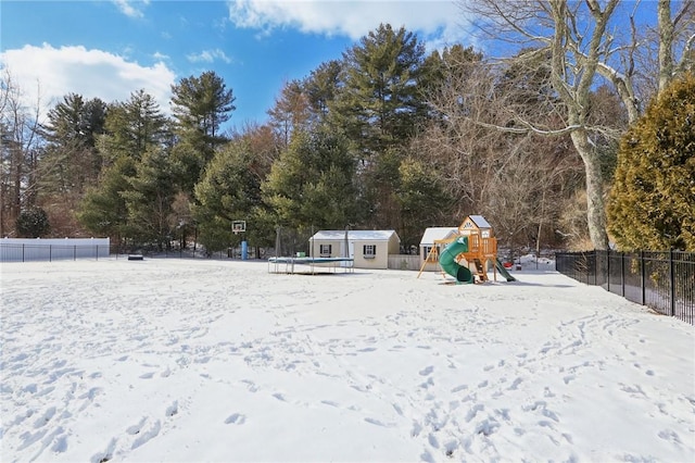 yard covered in snow featuring a playground and a storage unit