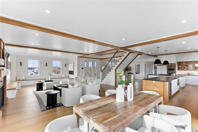 dining space with light hardwood / wood-style flooring and beamed ceiling