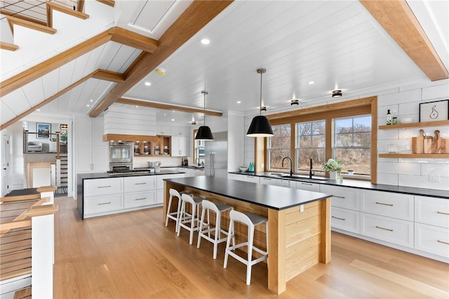 kitchen with pendant lighting, oven, white cabinets, a kitchen breakfast bar, and a center island