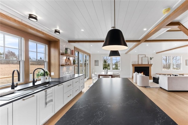 kitchen featuring white cabinetry, decorative light fixtures, beamed ceiling, and light wood-type flooring