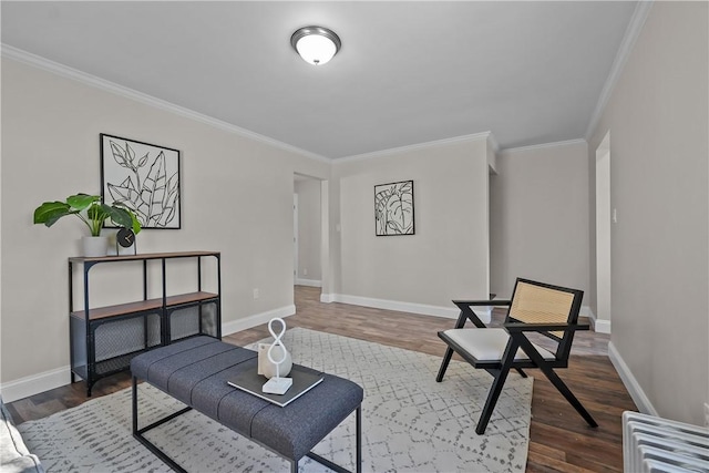 sitting room with ornamental molding and dark wood-type flooring