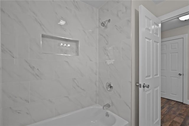 bathroom with hardwood / wood-style flooring and tiled shower / bath combo