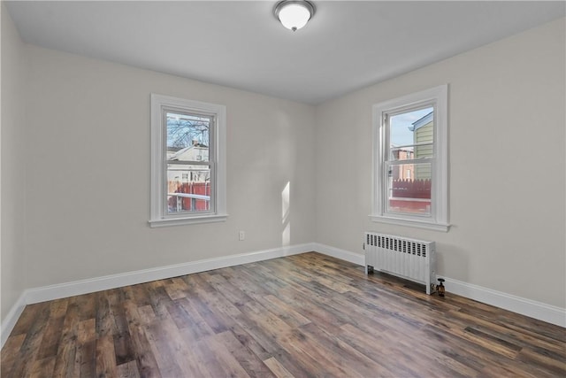 unfurnished room featuring radiator heating unit and dark hardwood / wood-style flooring