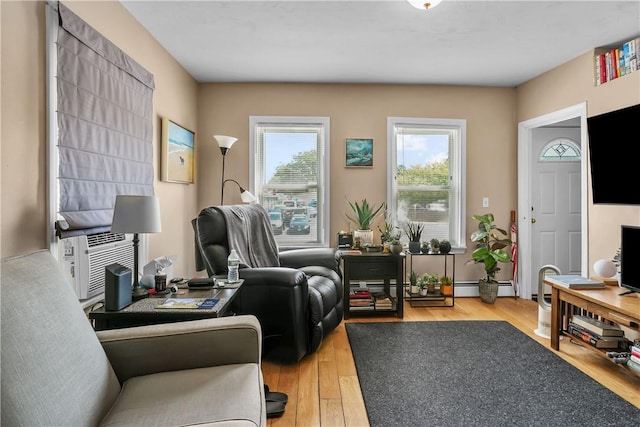 living room with a baseboard heating unit and wood-type flooring