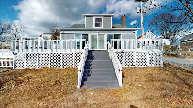 back of house with a chimney, a deck, stairway, and a shingled roof