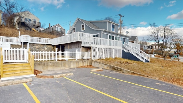 exterior space with uncovered parking, fence, stairs, and a deck