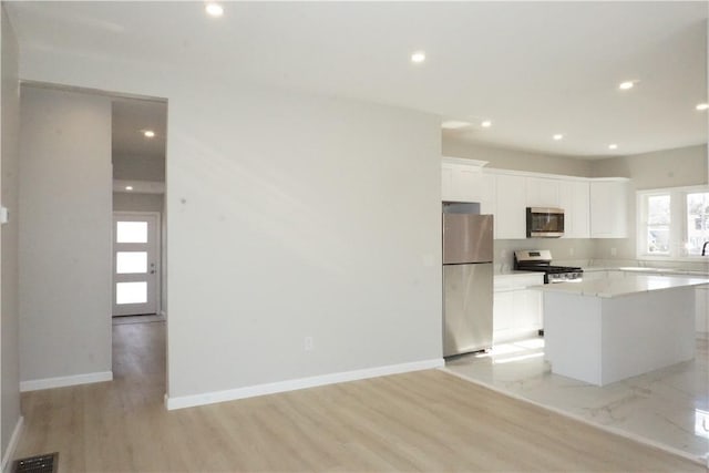 kitchen featuring white cabinetry, light hardwood / wood-style flooring, a center island, and appliances with stainless steel finishes