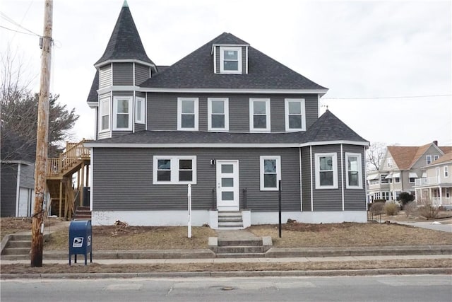 view of front of home featuring entry steps, a shingled roof, and stairway