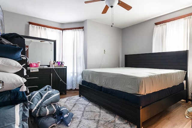 bedroom with ceiling fan, light hardwood / wood-style floors, and multiple windows