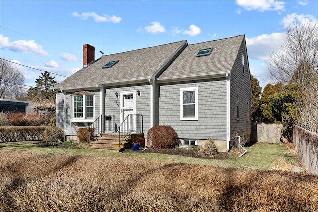 view of front of property featuring a front yard, a shingled roof, a chimney, and fence