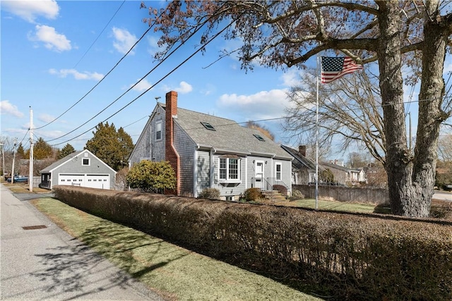 view of front of home featuring a detached garage, fence, entry steps, a chimney, and an outbuilding