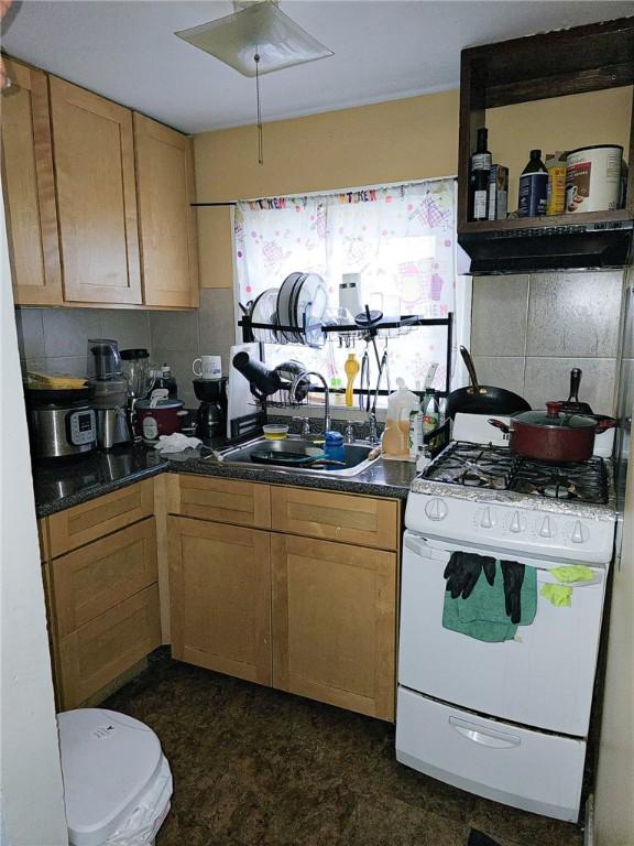 kitchen featuring decorative backsplash, sink, and white range with gas stovetop