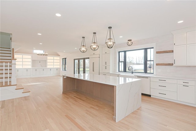 kitchen with a spacious island, white cabinetry, decorative light fixtures, dishwasher, and light stone countertops