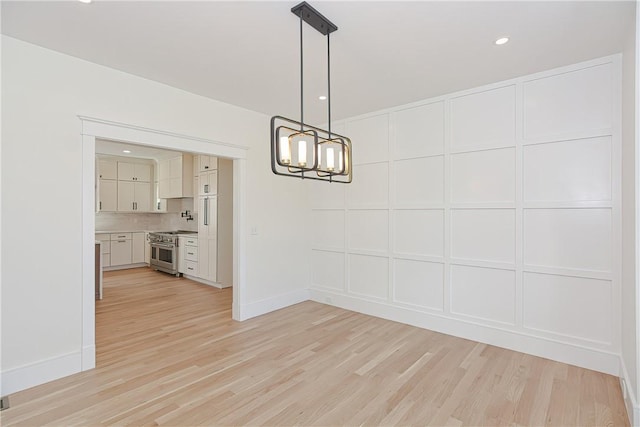 unfurnished dining area featuring an inviting chandelier and light wood-type flooring