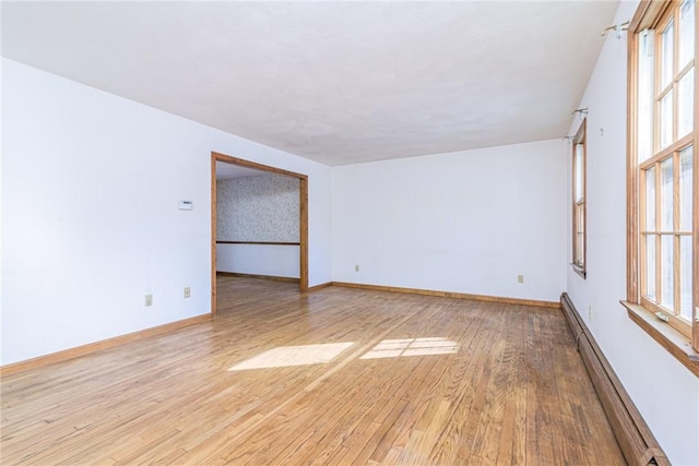 empty room featuring a baseboard radiator and light hardwood / wood-style floors