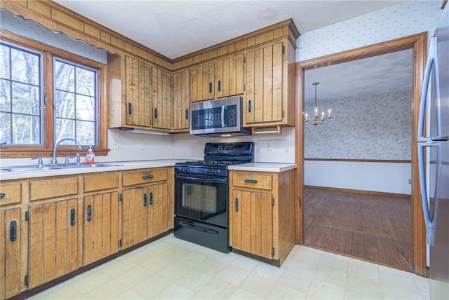 kitchen with stainless steel appliances, sink, a notable chandelier, and a textured ceiling