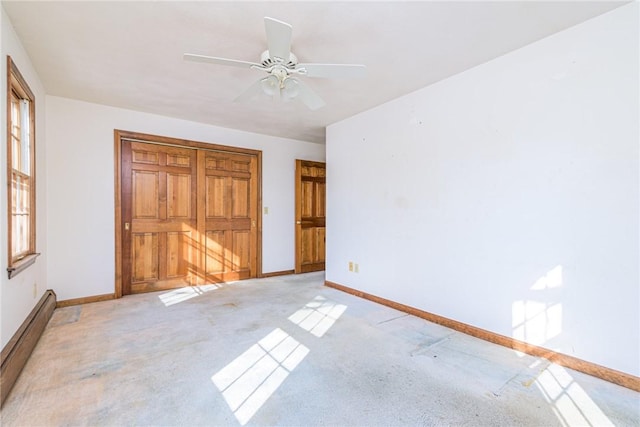 unfurnished bedroom with light carpet, a baseboard radiator, and ceiling fan