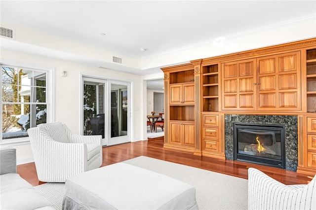 living room with hardwood / wood-style flooring, a premium fireplace, and crown molding