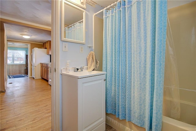 bathroom featuring wood-type flooring, shower / bath combination with curtain, crown molding, and vanity