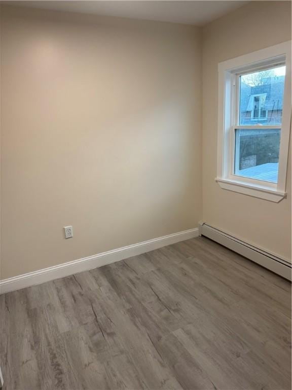 unfurnished room featuring a baseboard radiator and light hardwood / wood-style flooring