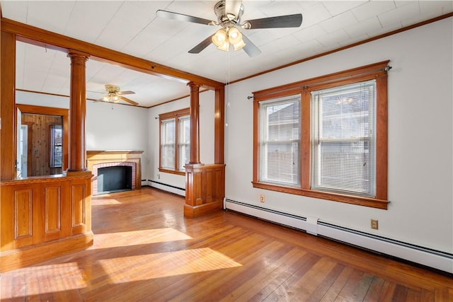 unfurnished living room featuring decorative columns, ornamental molding, baseboard heating, and light hardwood / wood-style floors