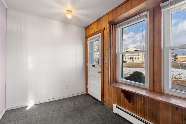 doorway with dark colored carpet, a baseboard radiator, and wood walls