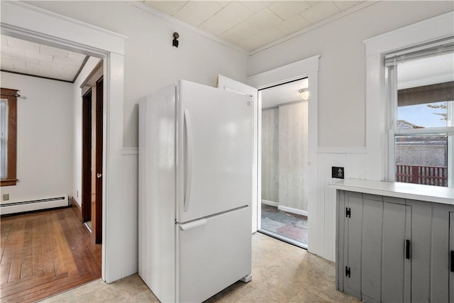 kitchen with white refrigerator, ornamental molding, and baseboard heating