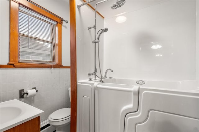 bathroom with baseboard heating, vanity, toilet, and tile walls