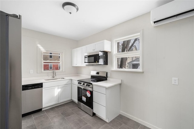 kitchen with tile patterned floors, sink, an AC wall unit, stainless steel appliances, and white cabinets