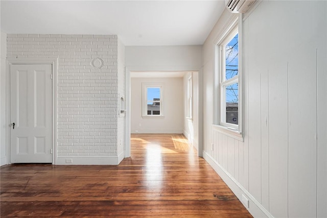 hallway with a wall mounted air conditioner, dark wood-type flooring, and brick wall