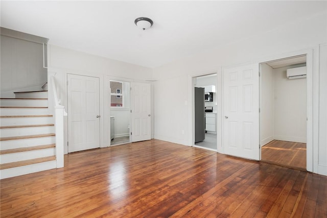 unfurnished living room featuring hardwood / wood-style flooring and a wall mounted AC