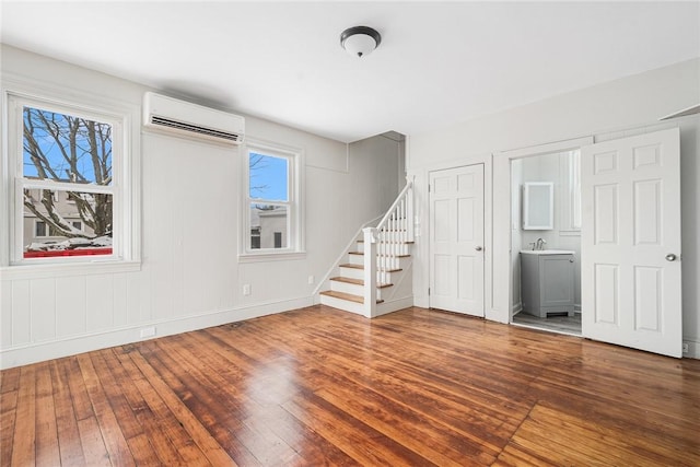 unfurnished living room with hardwood / wood-style flooring and an AC wall unit